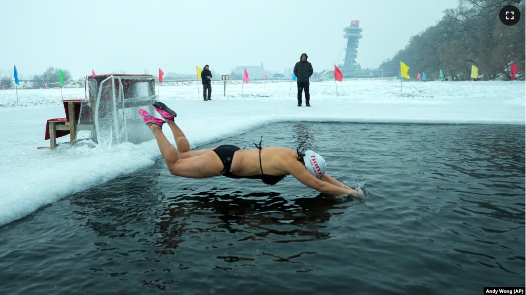 A woman jumps into a pool cut from the ice on the Songhua River in Harbin in northeastern China's Heilongjiang province, Tuesday, Jan. 7, 2025. (AP Photo/Andy Wong)