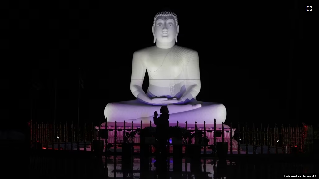 Carol Kruhen lifts up her pressed palms next to a statue of the Buddha after meditating at the New Jersey Buddhist Vihara and Meditation Center in Franklin Township, N.J. on Sunday Nov. 30, 2024. (AP photo/Luis Andres Henao)