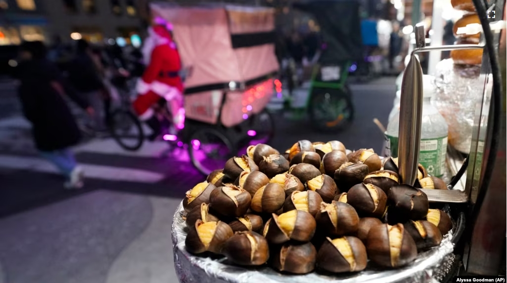 Chestnuts are displayed at a food vendor as a person dressed as Santa Claus offers rides, Thursday, Dec. 12, 2024, in New York. (AP Photo/Alyssa Goodman)