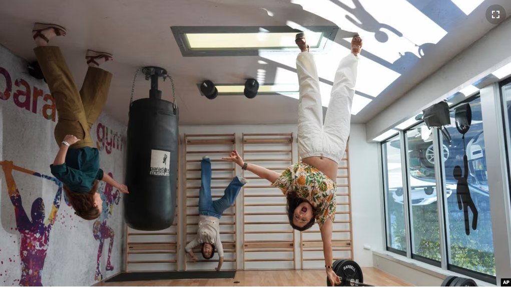 A group of friends pose for a picture that will be rotated upside down to create an optical illusion, at Paradox Museum Miami, Tuesday, Jan. 28, 2025, in Miami. (AP Photo/Rebecca Blackwell)