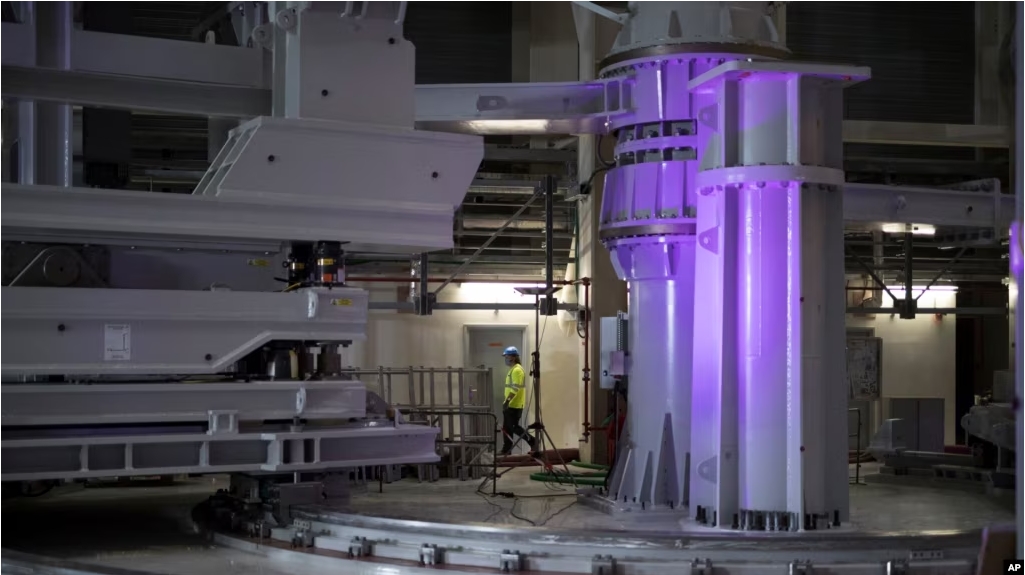 A worker walks through large assembly tools in the assembly hall of the ITER ( the International Thermonuclear Experimental Reactor). The project aims to replicate the energy of the sun to create nuclear fusion reactions as a way to produce power. (AP Photo/Daniel Cole)