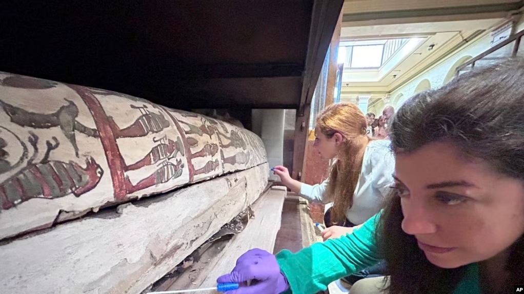 In this undated photo, Emma Paolin, PhD researcher at University of Ljubljana, background and Dr. Cecilia Bembibre, lecturer at the University College London take swab samples for the purpose of analysis at the Krakow University of Economics. (Abdelrazek Elnaggar via AP)