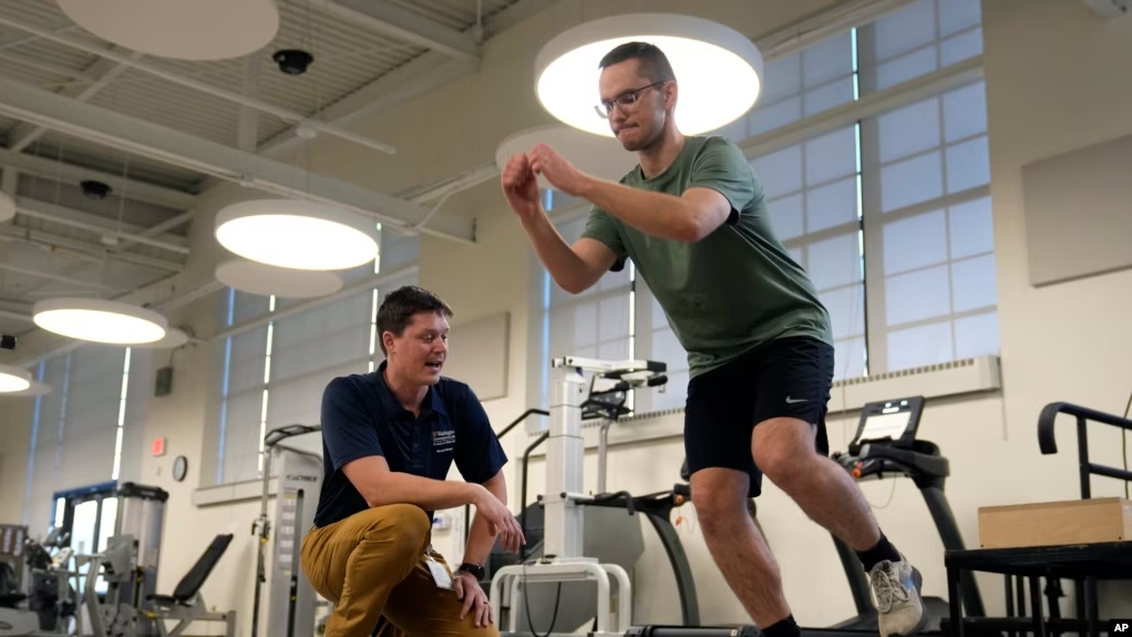 Physical therapist Tyler Detmer, left, works with patient Jacob Bullard at WashU, Monday, Dec. 16, 2024, in St. Louis. (AP Photo/Jeff Roberson)